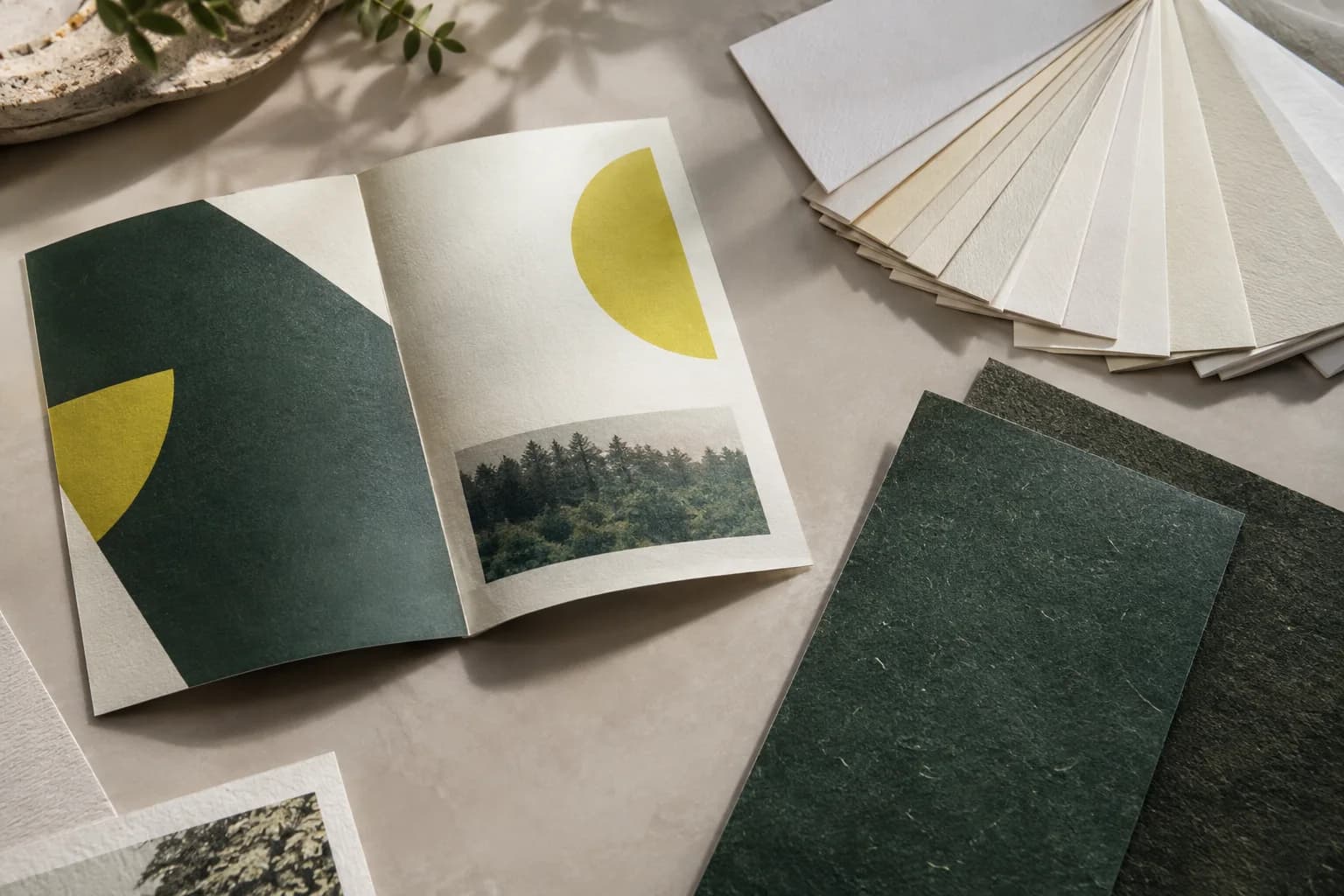 Folded print sample, cream paper swatches and dark textured stock.
